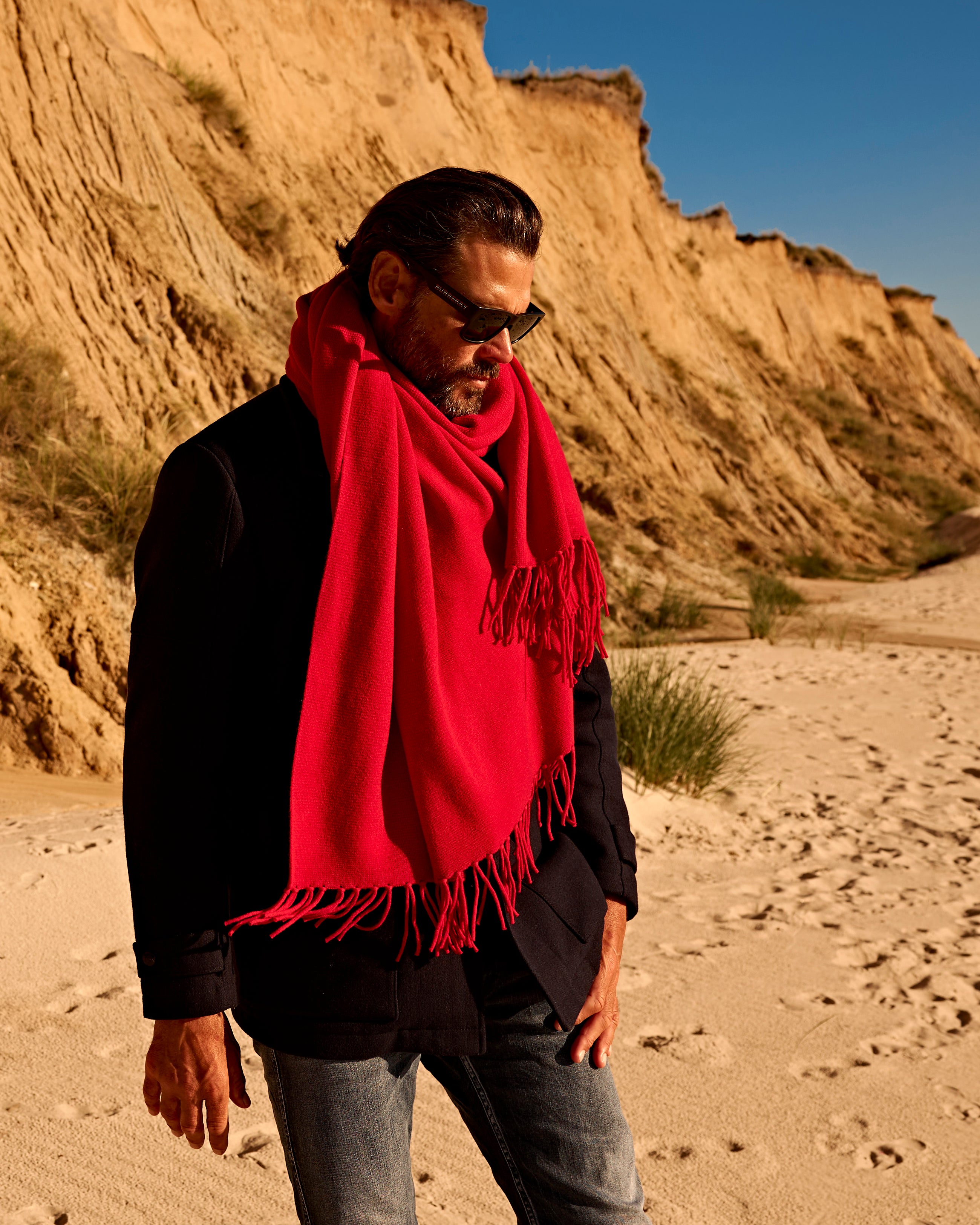 Mann am Strand mit EMAAL Schal in rot#Farbe_Feuerrot
