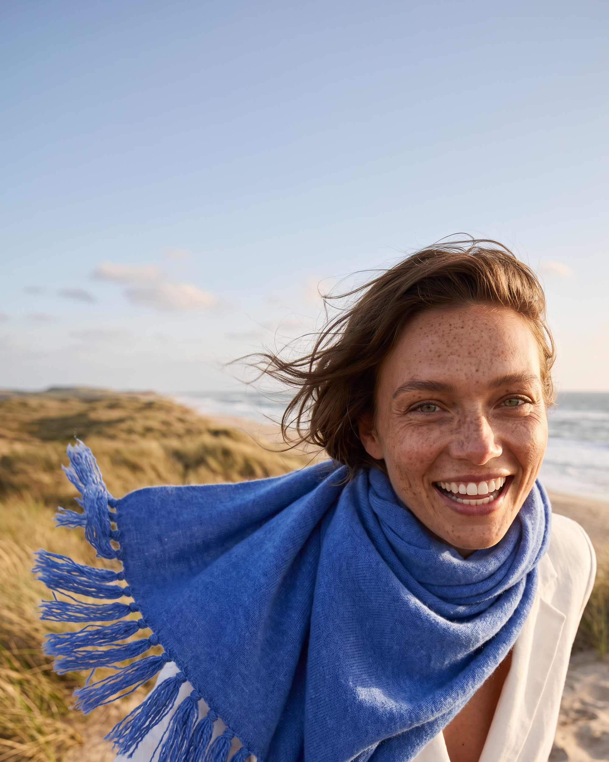 Portait von einer jungen Frau mit EMAAL CASHMERE Schal am Strand mit Milano Schal#Farbe_Jeansblau