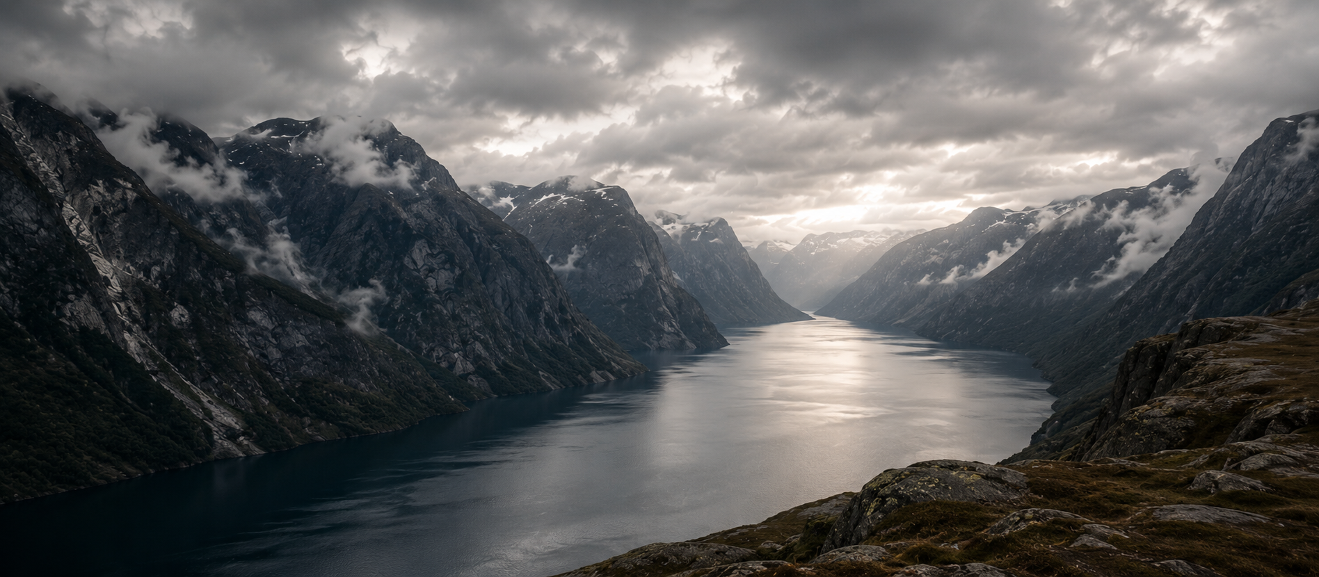 Dramatische Fjordlandschaft mit dunklen Bergen, Nebel und ruhigem Wasser – zeitlose Quiet Luxury Ästhetik inspiriert von nordischer Natur für Emaal Cashmere