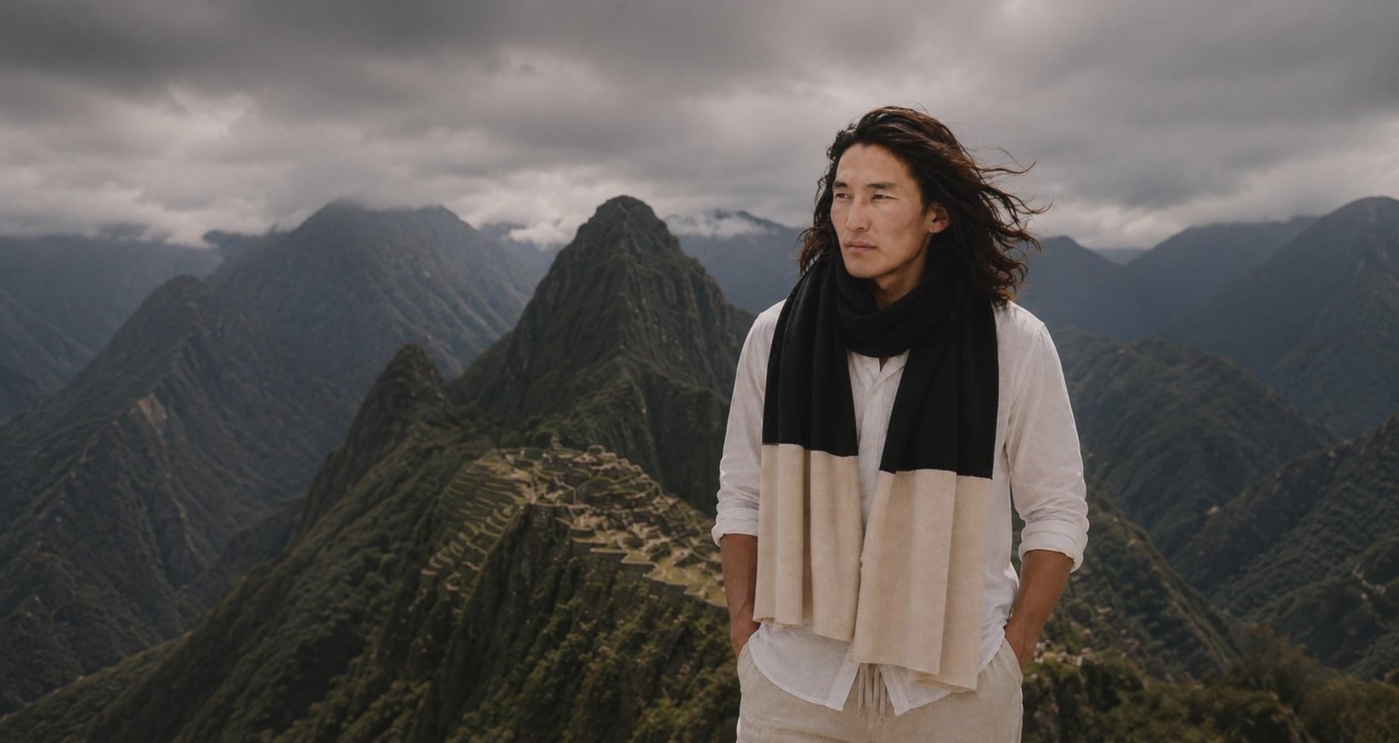 Stilvoller Mann mit Premium Cashmere Schal in dramatischer Landschaft mit Wetterwolken – moderne Eleganz und natürliche Schönheit von Emaal Cashmere